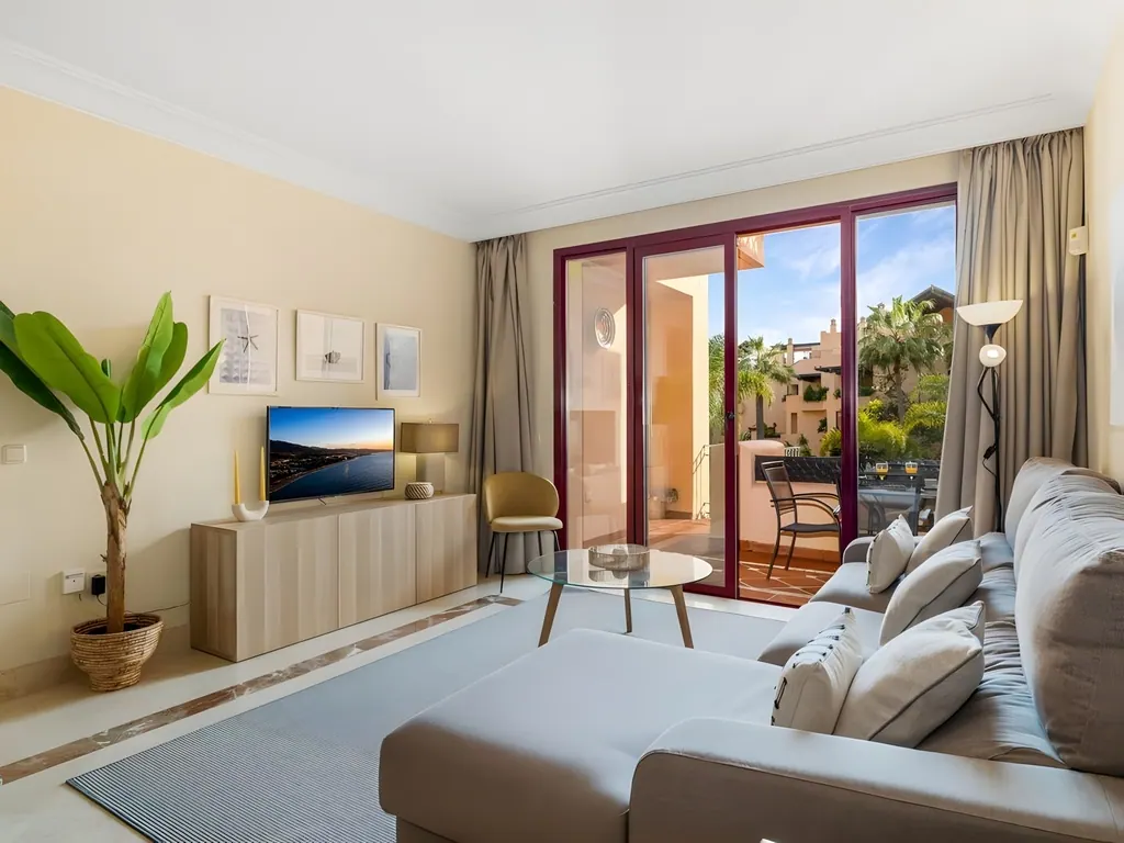 Apartment Bahía Alcántara Salón moderno con sofá gris, terraza y vistas tropicales