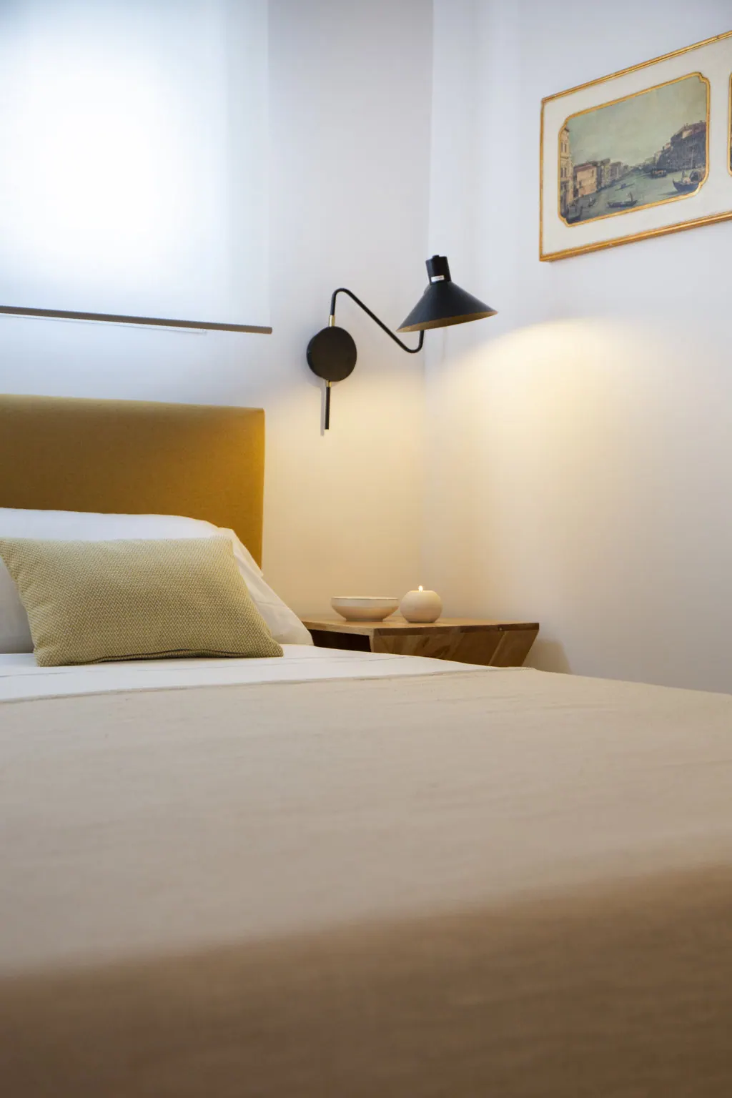 Holiday Home for Rent Dormitorio minimalista con lámpara de pared negra y cabecero mostaza