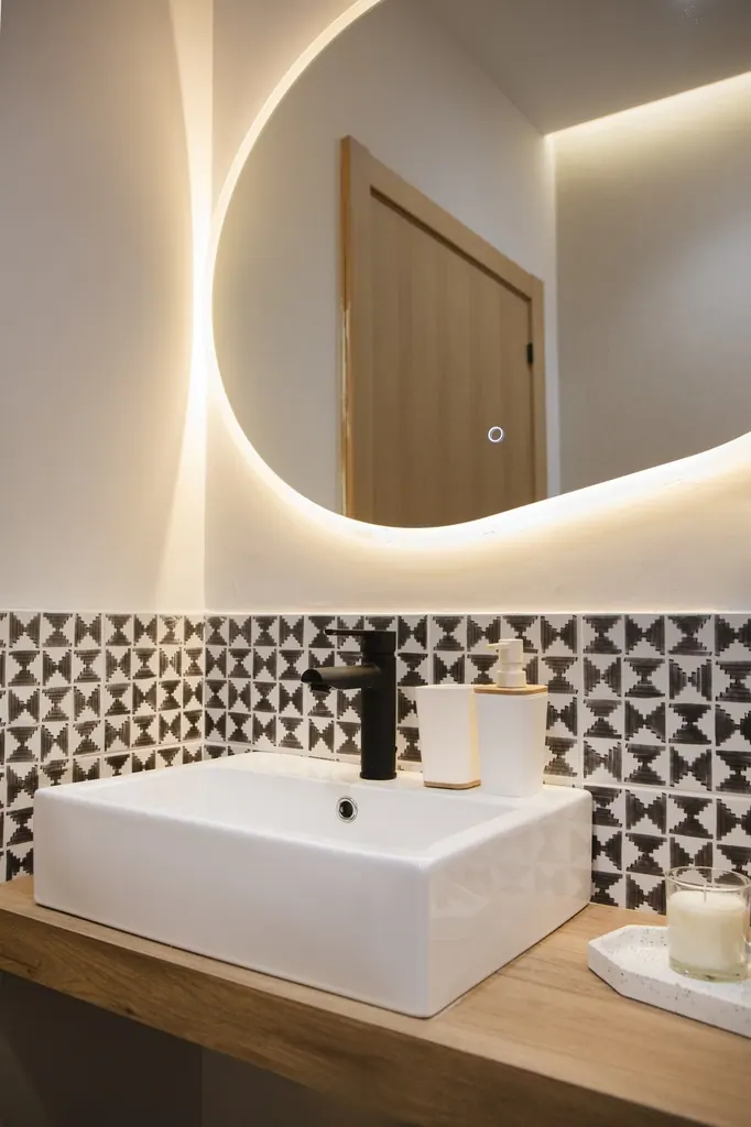 Holiday Home for Rent Baño moderno con espejo redondo iluminado y lavabo rectangular blanco