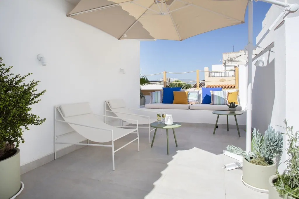 Holiday Home for Rent Terraza moderna minimalista con muebles blancos y sombrilla beige