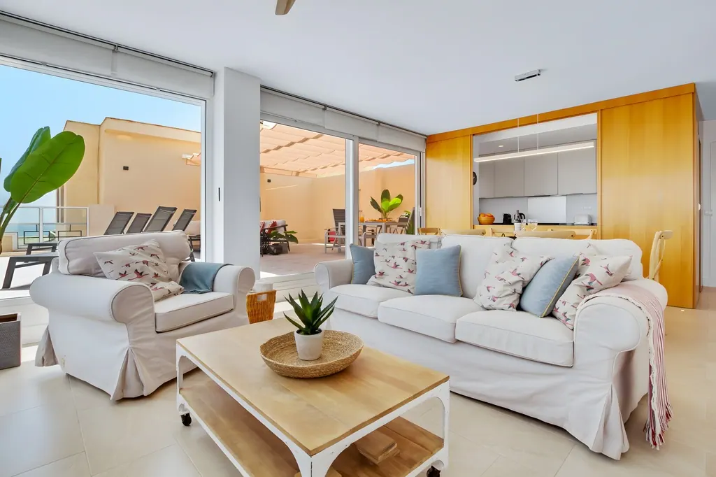 Penthouse la Carihuela Sala de estar moderna con sofás blancos y cocina integrada vista al exterior