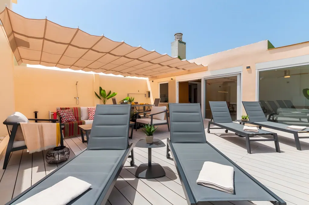 Penthouse la Carihuela Terraza moderna con tumbonas grises y toldo beige en ático