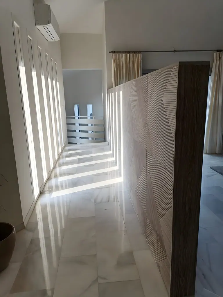 Villa Río Grande Pasillo moderno con luz natural filtrada por ventanas verticales y puertas decorativas