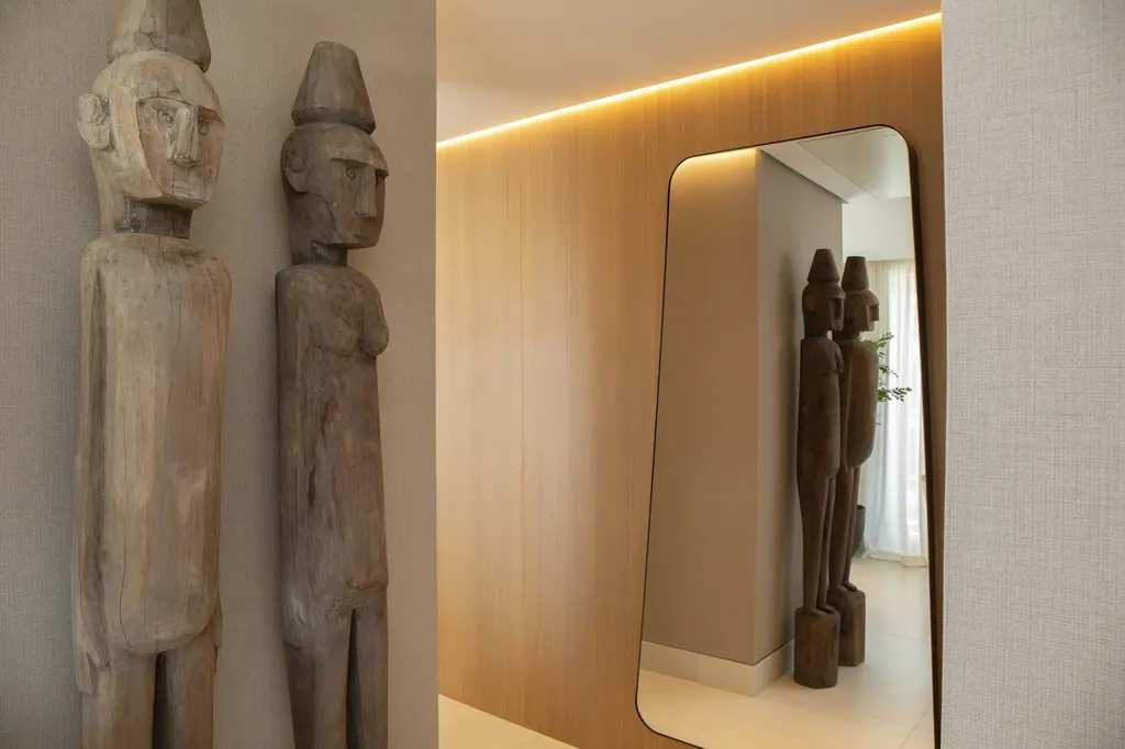 Esculturas africanas de madera junto a espejo moderno con iluminación cálida