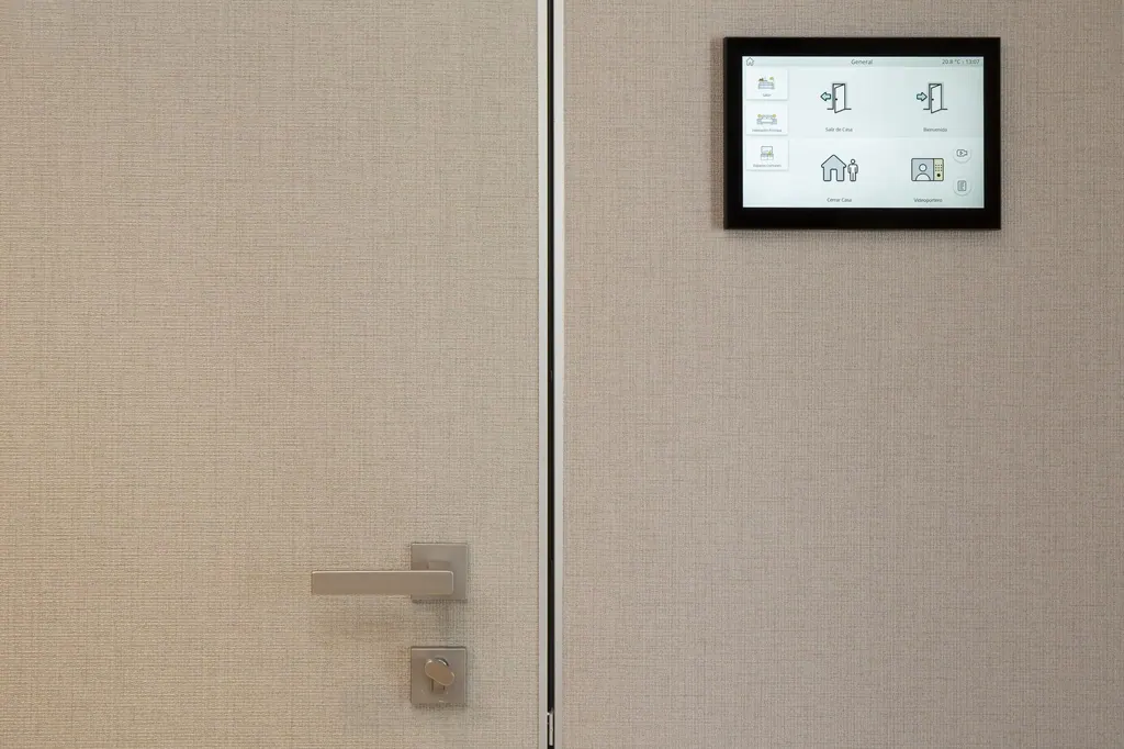 Panel de control domótico digital instalado en pared junto a puerta moderna