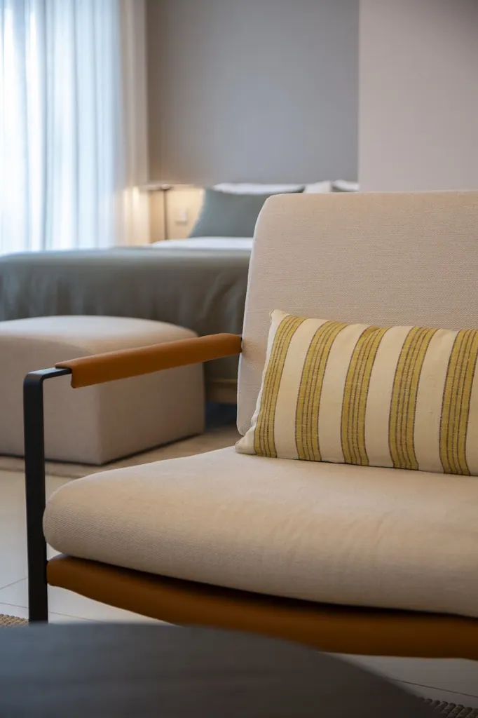 Sillón beige moderno con cojín de rayas en sala luminosa