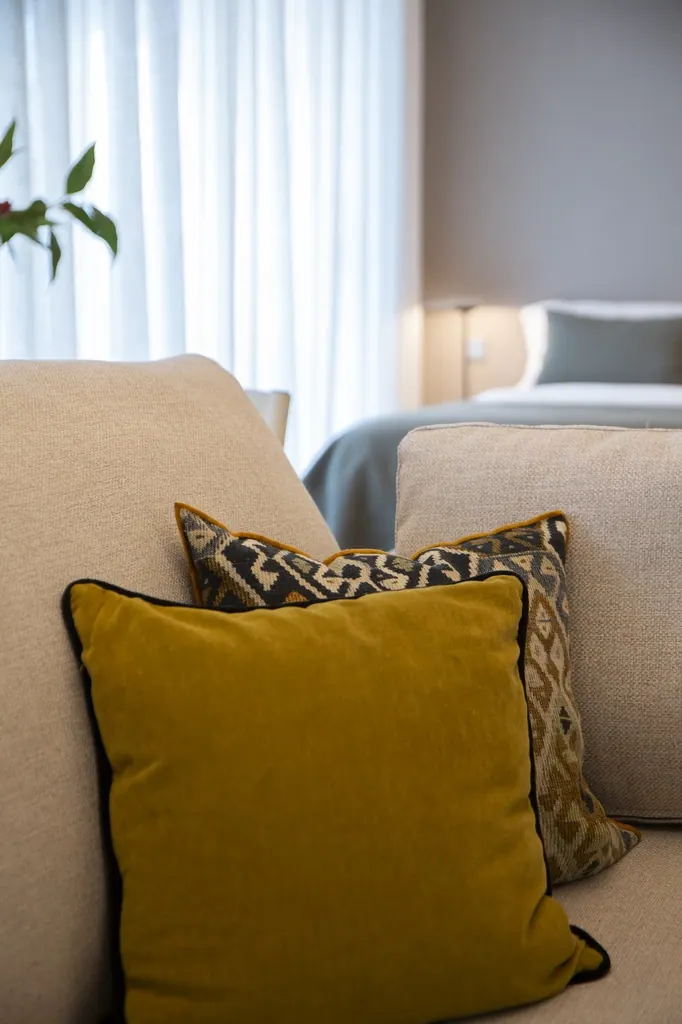 Cojines decorativos amarillo mostaza y estampado en sofá beige moderno
