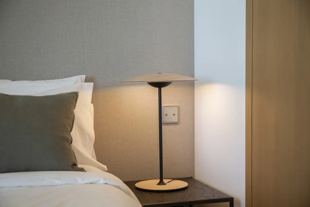 Lámpara de mesa moderna en dormitorio minimalista con cama blanca
