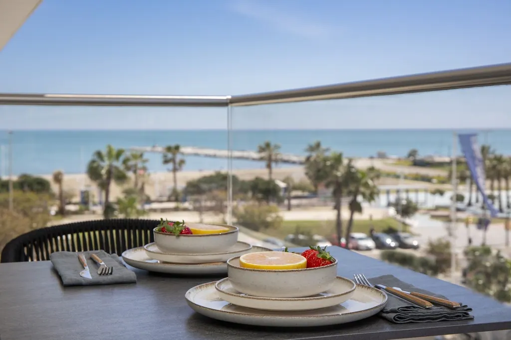 Mesa con postres y vista al mar mediterráneo con palmeras