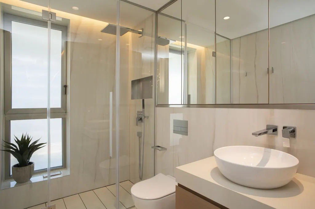Baño moderno minimalista con lavabo blanco sobre encimera y mampara de vidrio