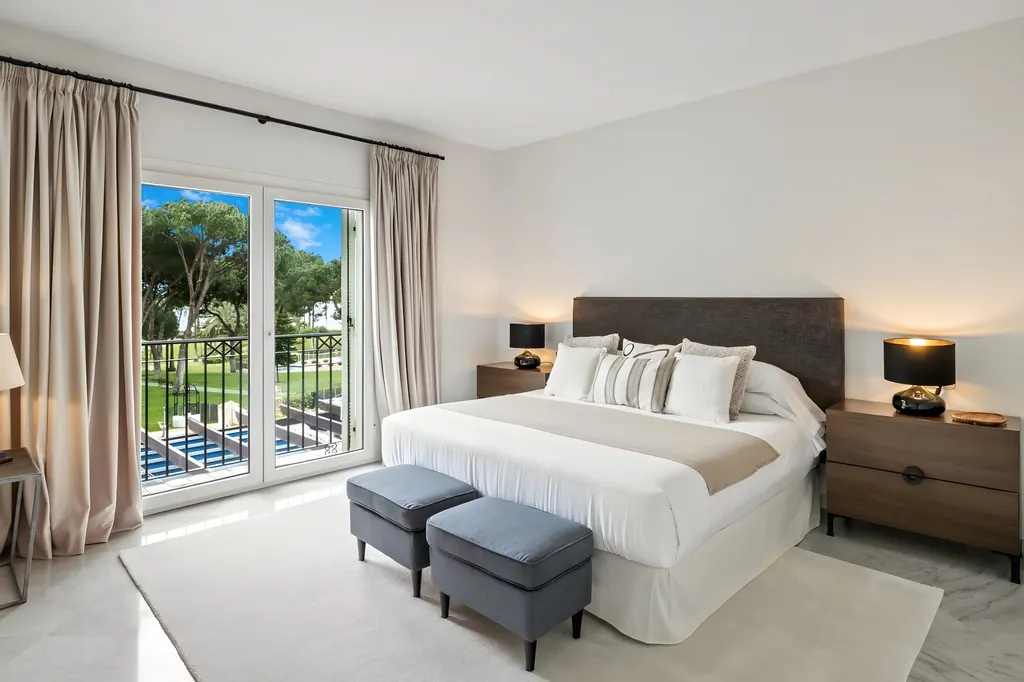 Dormitorio moderno con cama king size y balcón con vistas al jardín