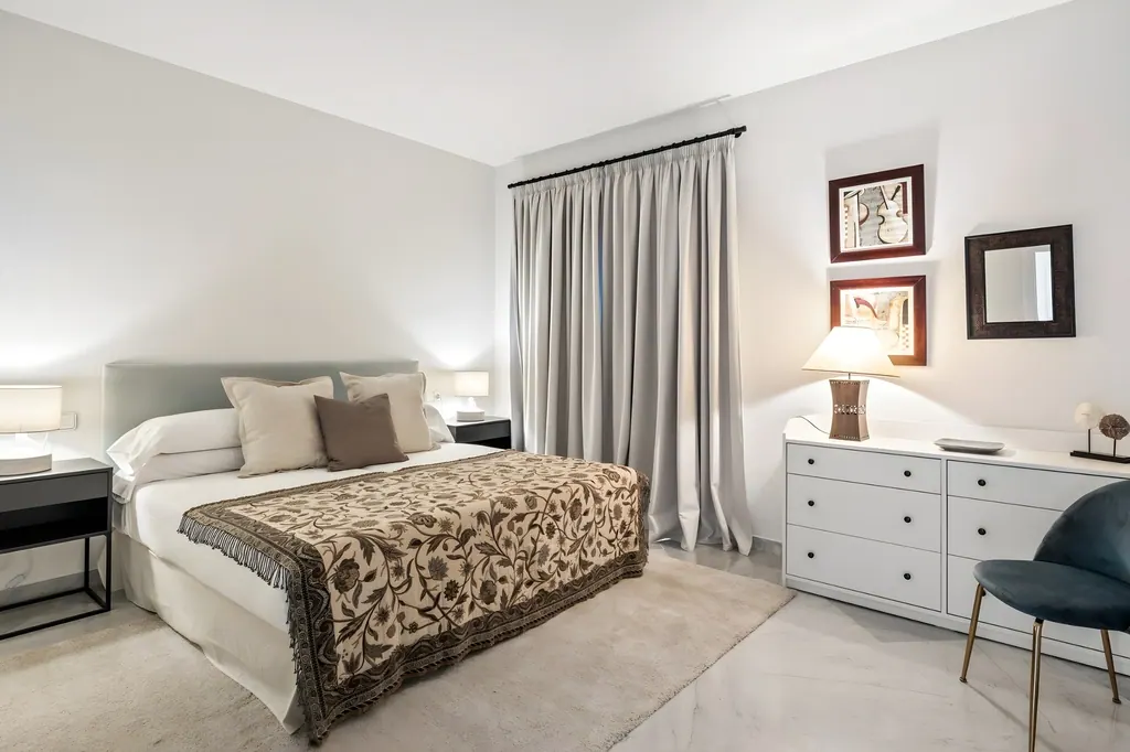 Dormitorio moderno con cama blanca, cortinas grises y cómoda blanca